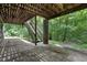 Covered patio featuring wooden stairs, lush trees, and natural light at 4272 Boyd Wright Rd, Burlington, NC 27215