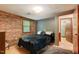 Brick walled bedroom with dark bedding and minimalist decor at 4272 Boyd Wright Rd, Burlington, NC 27215