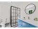 Bathroom featuring frameless shower, blue vanity with white countertop and round mirror at 4408 Queenstown Ct, Raleigh, NC 27612