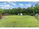 Large, grassy backyard with a tree line, sheds, and a small playhouse at 4575 Wendell Blvd, Wendell, NC 27591