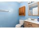 Cozy bathroom with blue walls featuring a wooden vanity, toilet, and framed mirror at 4575 Wendell Blvd, Wendell, NC 27591