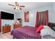 Cozy bedroom with striped bedding, a mounted TV, wooden dresser, and a ceiling fan at 4575 Wendell Blvd, Wendell, NC 27591