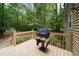 Wooden deck with grill and painted wooden railing looks out onto wooded backyard at 4710 Rollingwood Dr, Durham, NC 27713