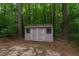 Storage shed with double doors sits nestled in the wooded lot at 4710 Rollingwood Dr, Durham, NC 27713