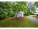 White outbuilding with gravel driveway access, complemented by a well-maintained lawn and mature trees at 4777 Helena Moriah Rd, Rougemont, NC 27572