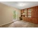 Bedroom with built-in bookshelves, desk, window overlooking greenery, and neutral-toned carpet at 506 E E St, Butner, NC 27509