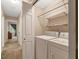 Functional laundry room with white washer and dryer, overhead shelving, and convenient access to the hallway at 506 E E St, Butner, NC 27509