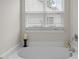 Close-up view of a pristine white bathtub with a window view, creating a relaxing atmosphere at 552 Stobhill Ln, Holly Springs, NC 27540