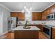 Well-lit kitchen featuring stainless steel appliances, wood cabinets, and a center island with pendant lighting at 552 Stobhill Ln, Holly Springs, NC 27540