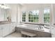 Luxurious bathroom with soaking tub, marble floors, and many windows with nature views at 636 Pendleton Lake Rd, Raleigh, NC 27614