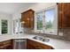 Kitchen boasts a stainless sink, wood cabinets, and granite counters, lit by bright windows at 636 Pendleton Lake Rd, Raleigh, NC 27614