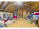Unfinished attic space with exposed beams, wood flooring, and storage solutions at 6949 Rex Rd, Holly Springs, NC 27540