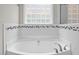 Luxurious soaking tub with sleek fixtures and a tiled surround, set beneath a privacy window at 6949 Rex Rd, Holly Springs, NC 27540