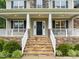 Inviting front porch with stone accents, classic columns, and a beautifully crafted entrance, leading to a warm home at 6949 Rex Rd, Holly Springs, NC 27540