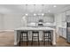 Spacious kitchen island with three stools, modern appliances, and recessed lighting at 6949 Rex Rd, Holly Springs, NC 27540