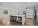 Bright, modern kitchen with stainless steel appliances, white countertops, and three-stool island at 6949 Rex Rd, Holly Springs, NC 27540