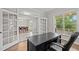 Bright office with wooden floors, a large desk, and views of the dining room and outdoors at 6949 Rex Rd, Holly Springs, NC 27540