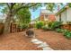 The spacious backyard features a stone pathway, fire pit, lush greenery, and wood storage at 729 Mial St, Raleigh, NC 27608