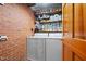 Efficient laundry area with brick wall, shelving, and modern washer and dryer units at 729 Mial St, Raleigh, NC 27608