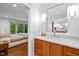 Stylish bathroom featuring wood cabinets, marble countertops, and modern fixtures, with a glimpse of the bedroom at 800 Shady Lawn Rd, Chapel Hill, NC 27514