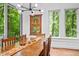 Bright dining room with wooden table, modern chandelier, and large windows with views of the trees at 800 Shady Lawn Rd, Chapel Hill, NC 27514