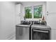 Laundry room with stainless steel washer and dryer, bright window, and cabinet storage above at 800 Shady Lawn Rd, Chapel Hill, NC 27514