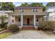 Inviting home featuring a charming front porch with white pillars, a red front door, and a well-maintained landscaped yard at 803 W Club Blvd, Durham, NC 27701