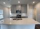 Kitchen island with double sink, gray cabinets, and stainless steel appliances in a naturally lit space at 909 Clearhaven Ln # 909, Fuquay Varina, NC 27526