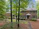 Charming brick home with black shutters, an American flag, and mature trees in the front yard at 102 Mel Oak Dr, Chapel Hill, NC 27516