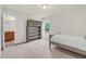 Carpeted bedroom featuring natural light, a twin bed with neutral bedding, and an open doorway to the ensuite bath at 106 Elmsford St, Durham, NC 27703