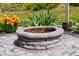 Close-up of a circular stone fire pit surrounded by colorful flowers and lush greenery, creating a cozy ambiance at 106 Elmsford St, Durham, NC 27703