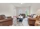 Open living room featuring matching leather sofas, a decorative rug, and large windows at 106 Elmsford St, Durham, NC 27703