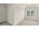 Bright walk-in closet featuring white walls, carpeted floors, a window and built-in wire shelving for optimal storage at 106 Elmsford St, Durham, NC 27703