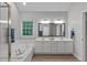 Light-filled bathroom showcases a double vanity, separate tub, and wood-look flooring at 1208 Mossy Glade Cir, Apex, NC 27502