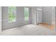 Cozy carpeted living room featuring two bright windows, neutral walls, and white trim at 1208 Mossy Glade Cir, Apex, NC 27502