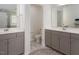 Bright bathroom featuring double sinks, vanity with gray cabinets, and separate toilet room at 1213 Grenshaw Dr, Morrisville, NC 27560