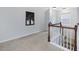 Bright upstairs hallway with carpet and wooden railing; perfect for connecting bedrooms and other living spaces at 136 Shadow Hawk Dr, Durham, NC 27713