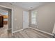 Bedroom features a large window, neutral colored walls, wood-look flooring, and an interior door at 139 Carriage Hill Dr, Stem, NC 27581