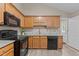 Bright kitchen features wood cabinets, black appliances, granite countertops, and wood-look flooring at 139 Carriage Hill Dr, Stem, NC 27581