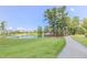 Scenic view of a community pond with a walking path, mature trees, and lush green lawn, creating a tranquil setting at 1920 Bright Kannon Way, Wendell, NC 27591
