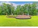 Community playground area featuring mature trees, lush grass, swing sets, and a slide at 1984 Sadler Ave, Creedmoor, NC 27522