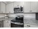 Modern kitchen featuring granite countertops, stainless steel microwave and stove with gray cabinets at 200 Gill Farm Way, Franklinton, NC 27525