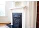 Close-up of a fireplace with white mantle and ornate iron detailing with a window to the left at 208 Glenn St, Franklinton, NC 27525