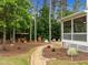 Landscaped backyard featuring a screened porch, wood bench, and mulch beds near a wooded area at 21 Botanical Way, Pittsboro, NC 27312