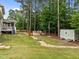 Landscaped backyard with a wood bench, fire pit, shed, and small wooden bridge at 21 Botanical Way, Pittsboro, NC 27312