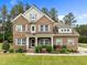 Beautiful two-story brick home with a manicured lawn, complemented by lush landscaping and gray shutters at 21 Botanical Way, Pittsboro, NC 27312