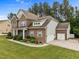 Side view of a brick home, featuring an attached two-car garage and well-kept landscaping at 21 Botanical Way, Pittsboro, NC 27312
