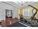 View of a home gym with hardwood floors, coffered ceiling, and workout equipment, leading to a bedroom at 21 Botanical Way, Pittsboro, NC 27312