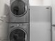 Laundry area featuring stacked washer and dryer units next to a refrigerator at 21 Botanical Way, Pittsboro, NC 27312