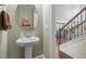 Bright powder room features a pedestal sink with an oval mirror and views of the staircase and kitchen at 21 Botanical Way, Pittsboro, NC 27312